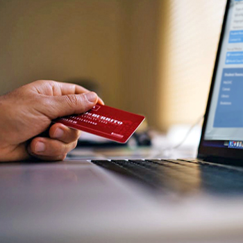 a hand holding a credit card while looking at the GHC Foundation's online giving page