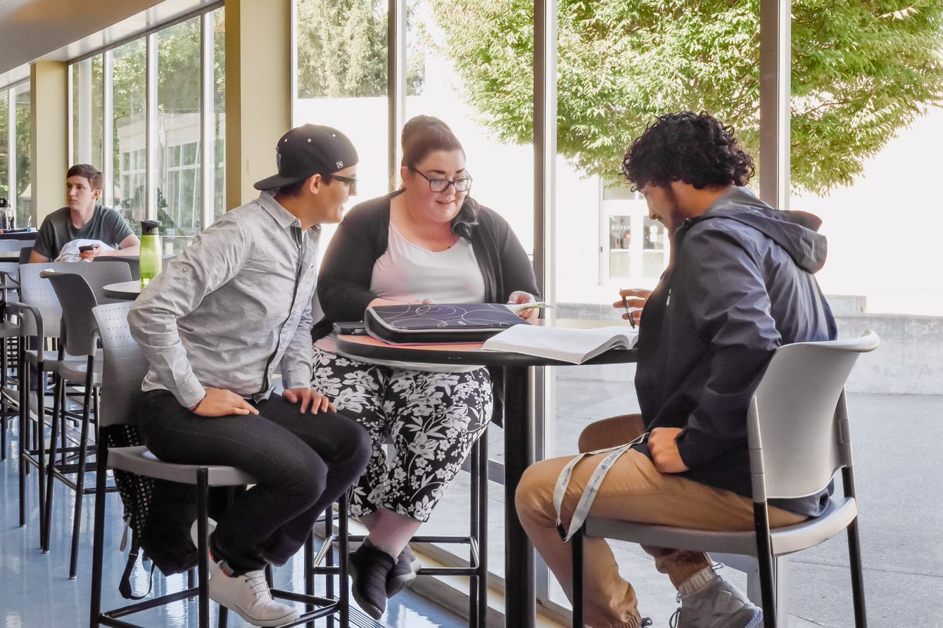 Students sitting at a table discussing a book