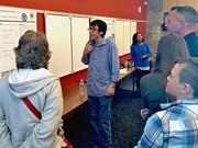 a summer research student giving a "thumbs up" to a poster