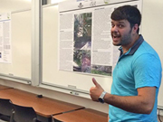 a summer research student giving a "thumbs up" to a poster