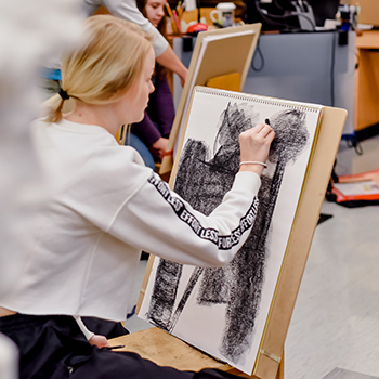 Artist sitting at an easel working on a piece
