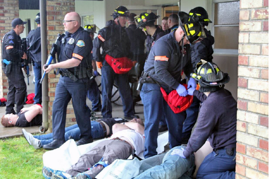 emergency respondors and victims gathered in a safe space outside of building