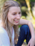 Analiisa sits in a casual pose for a professional photo. She is looking off to the side of the camera and wearing a white shirt and skinny jeans.