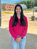 Anica stands for a headhot on the GHC campus. She is wearing a salmon pink sweater and light wash jeans. 