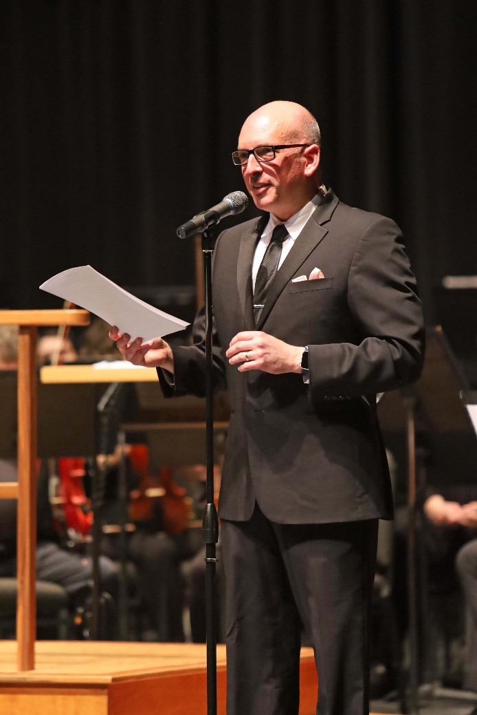 Dr. William Dyer standing on a stage at a microphone stand