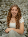 Hazel sits on a rocky beach and poses for the camera. 
