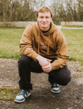 Kohan Morrison poses in a crouch infront of a field. 