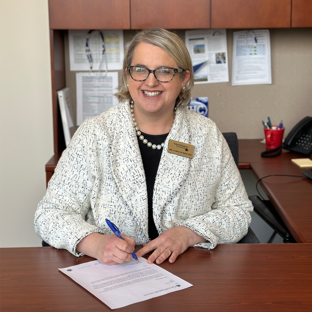 GHC President Dr. Carli Schiffner signs a letter congratulating a student for earning a spot on the President's Honor List.