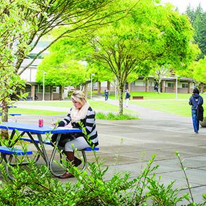 Photo of student sitting at a picnic table in the courtyard.