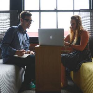 Two people sitting looking at a computer