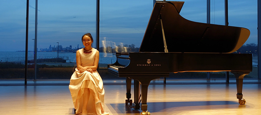 Dr. Yiyi Chen sitting near a piano