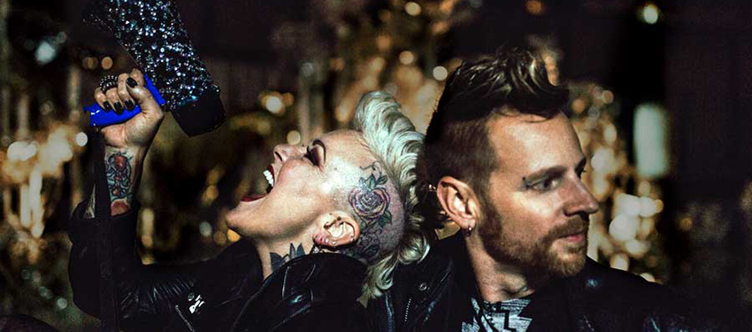 Two band members singing with other band members and instruments in the background