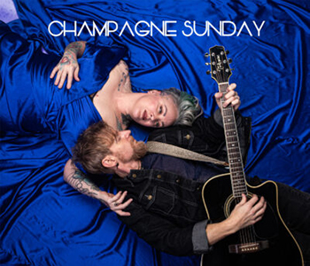 two people laying in blue blankets with one holding a guitar and the words champagne sunday above