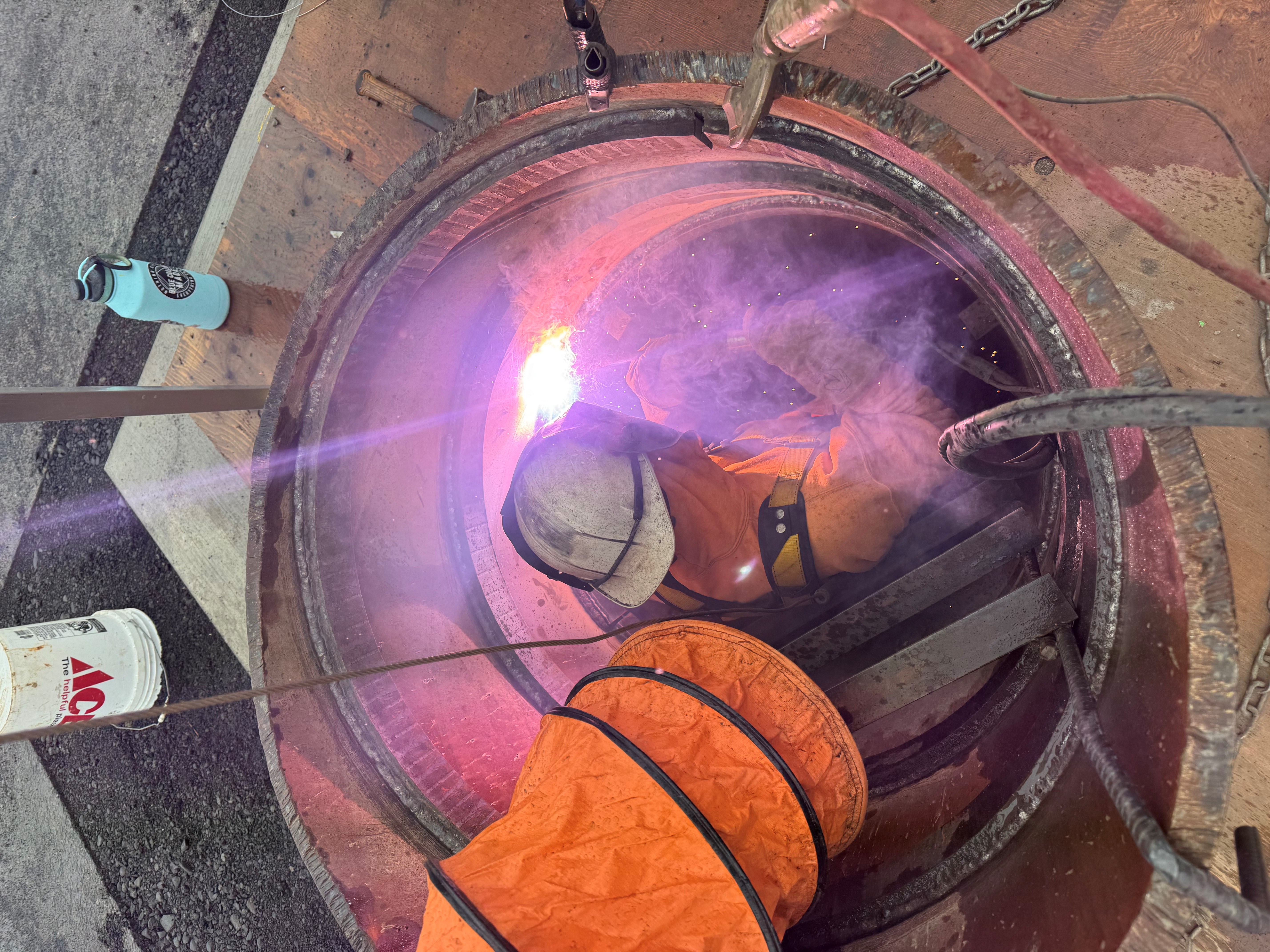 Andrew Benson working on the underside of a metal beam, the picture is taken from an artistic angle so the sparks coming off the equiptment seem to leave in an arch.