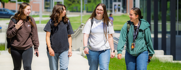 A collage of four images. The first is exterior architectural shot of the outside of the tulalW Student Center, second Charlie choker pointing at the camera infront of a whiteboard that reads "New Student Orientation", third students walking casually in a group across campus, laughing at something said. And forth, the Grays Harbor College logo over the exterior of the campus bookstore