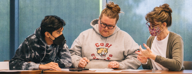 The text "Enrollment & Registration Sessions" over a cloudy background, to the left is a cut out image of a student getting help with paperwork from two staff.