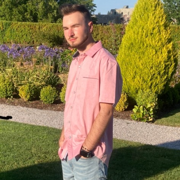 Justin Inoan Pop standing in grass in front of colorful plants