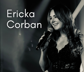 A black and white photo of Ericka Corban singing for a crowd with a smile on her face.