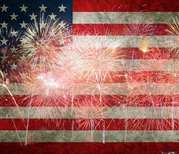 An aged American flag with red and white fireworks overlayed on top.
