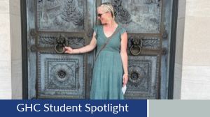 Student Spotlight, Lisa Getty. Lisa poses infront of intricate metal doors, pulling lightly on a ringed handle.